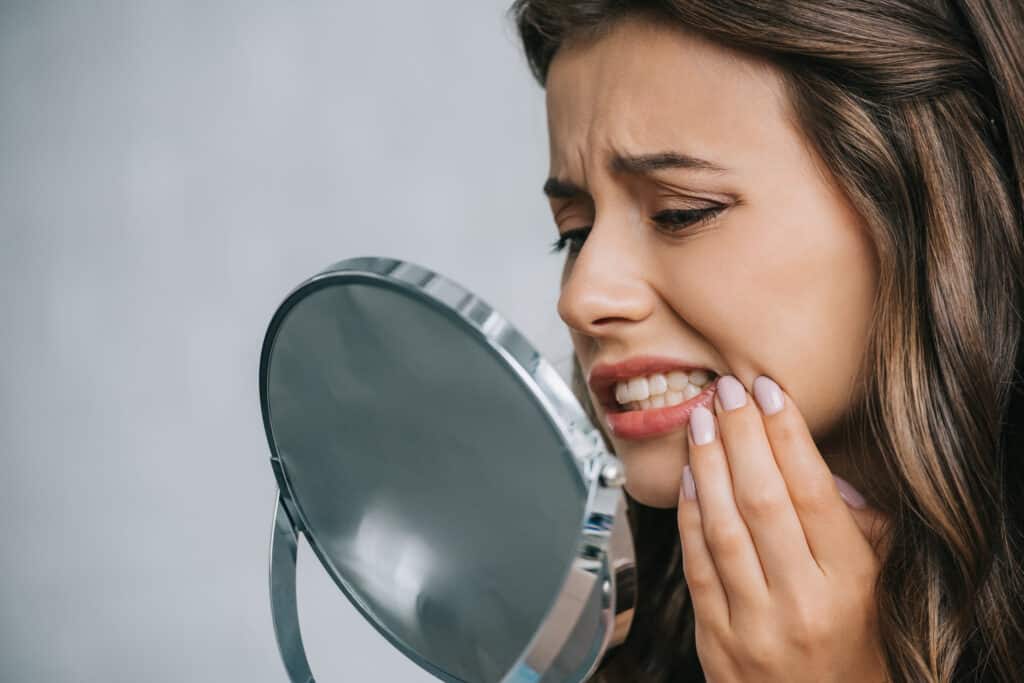 Close-up view of young woman having toothache and looking at mirror
Are Teeth Naturally Yellow or White?