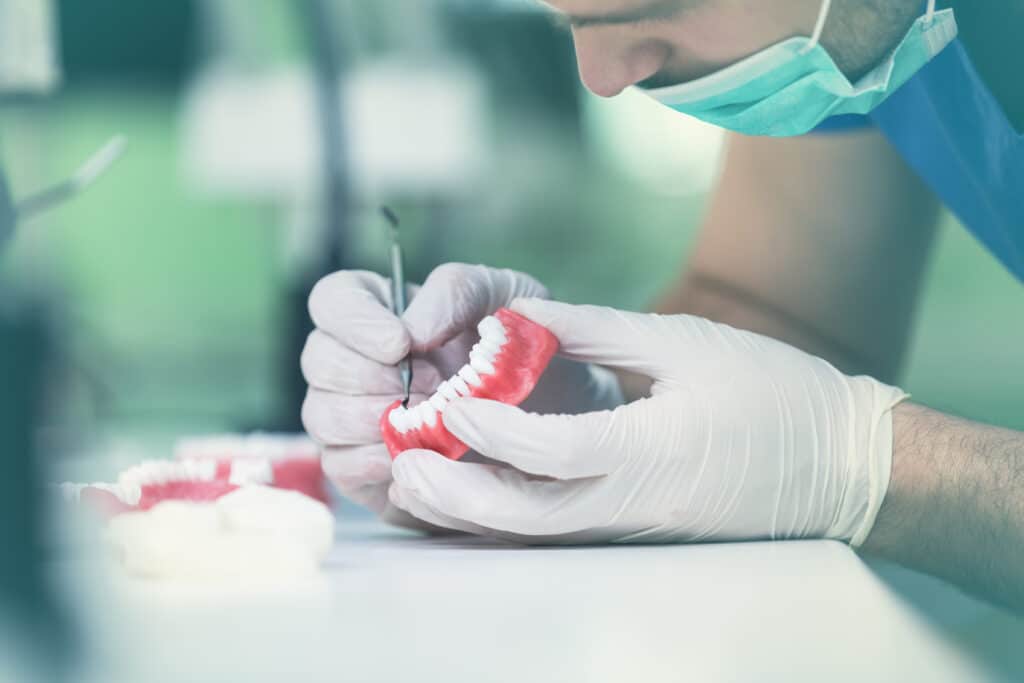 Dental prosthesis, dentures, prosthetics work. Dental students while working on the denture, false teeth, a study and a table with dental tools. Finding the Right Dentures for You