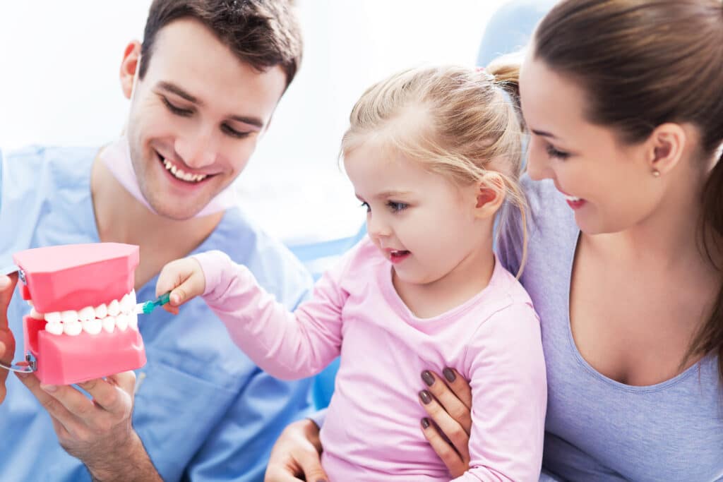 Dentist teaching girl how to brush teeth
dental care for children