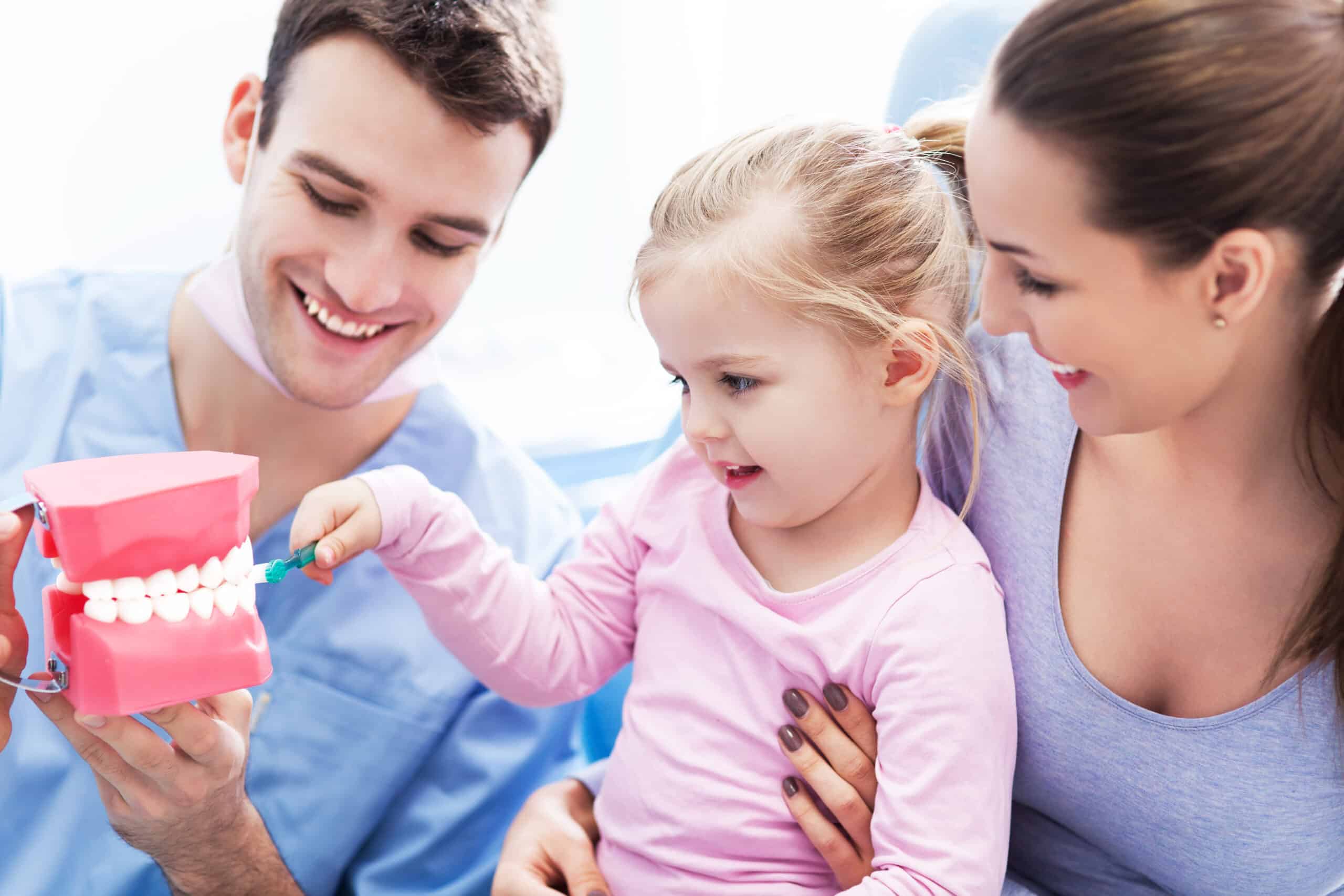 Dentist teaching girl how to brush teeth dental care for children